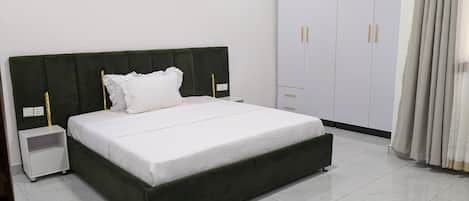 A bed with a dark headboard, white bedding, and two bedside tables with lamps.