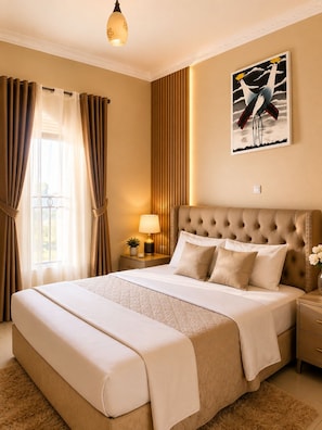 Una habitación de hotel con una cama grande, una mesita de noche con lámpara, un cuadro en la pared y una ventana con cortinas.