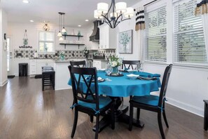 Un coin repas avec une nappe bleue, des chaises noires et un lustre.