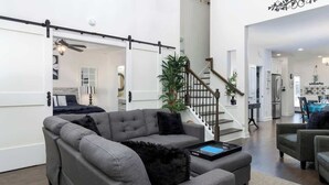 Una sala de estar moderna con un sofá seccional, una mesa de centro y una escalera que conduce a un nivel superior.