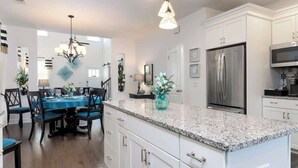 Una cocina moderna con armarios blancos, encimera de granito y electrodomésticos de acero inoxidable.