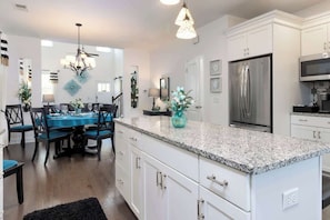 A modern kitchen with white cabinetry, a granite countertop, and stainless steel appliances.