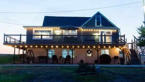 Une maison à deux étages dotée d’un balcon, de guirlandes lumineuses, d’un espace salon extérieur et d’un patio couvert.