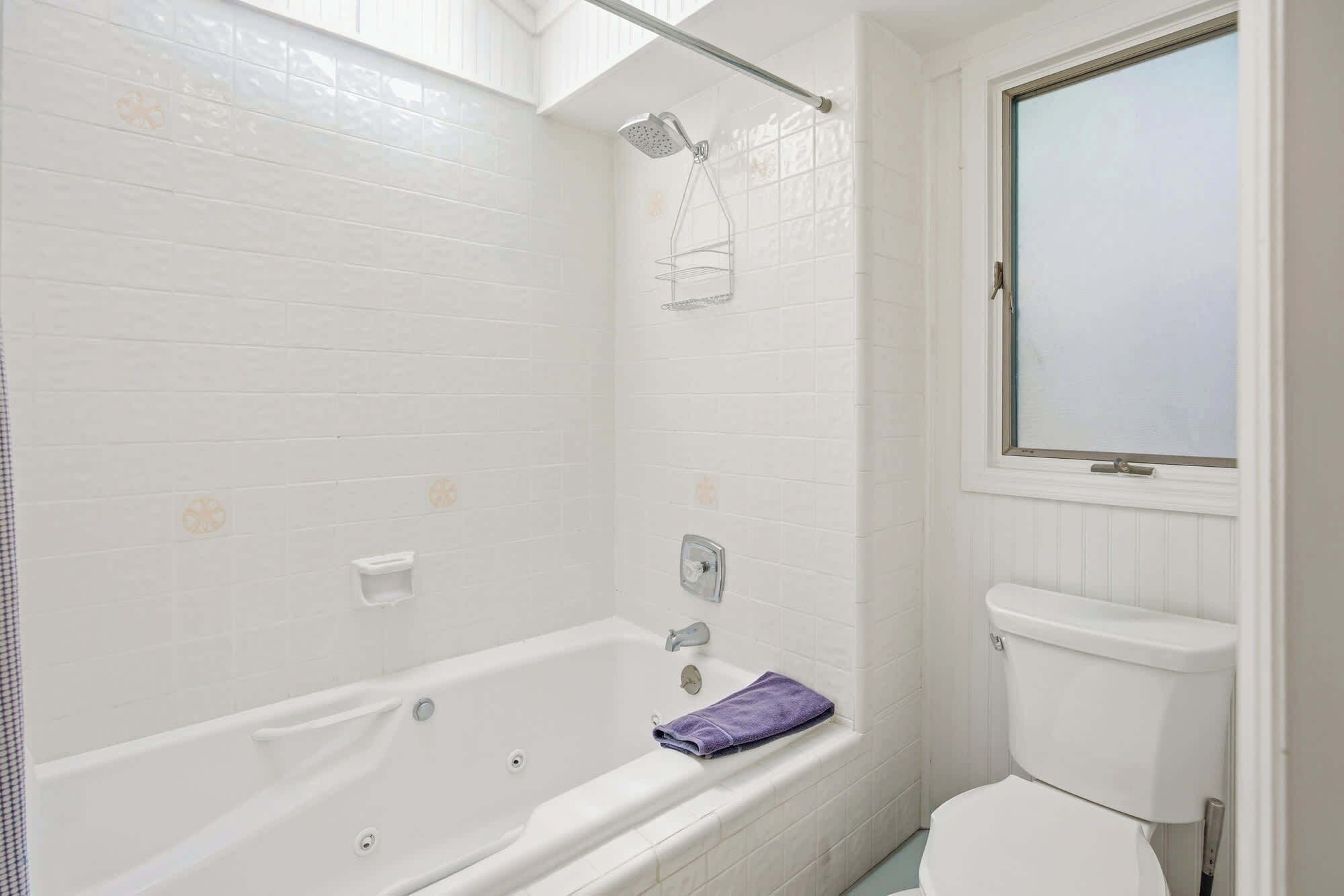 A bathroom with a white bathtub, a shower, and a toilet.