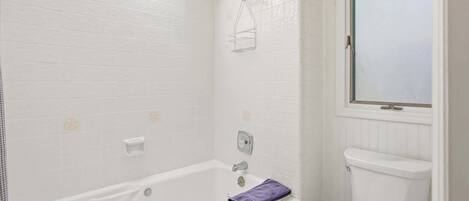 A bathroom with a white bathtub, a shower, and a toilet.