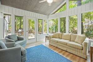 A sunroom with a sofa, chairs, and a view of the outdoors.