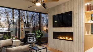 A modern living room with a fireplace, a large TV, and a comfortable seating area.
