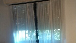 A bedroom with a bed, a window with sheer curtains, and a radiator above the window. - CASA CHALET LAMAR (whole house) (Santa Clara del Mar)