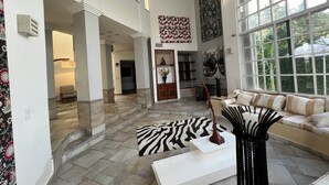A spacious living area with a large window, a zebra-patterned rug, and a modern sofa.