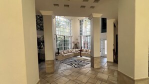 A spacious hallway with a large window, a seating area with cushions, and a zebra-patterned rug.
