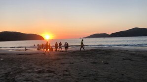 A beach scene at sunset with people gathered on the sand. - Villa Soleil (Zihuatanejo)