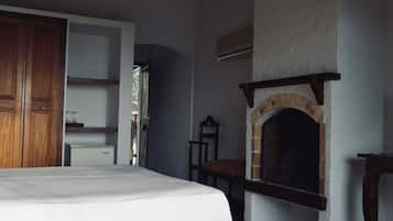 Ein Schlafzimmer mit einem Bett, einem Holzschrank, einem Kamin aus Ziegelsteinen und einem kleinen Tisch mit Stuhl.
