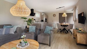 A modern living room with a sofa, armchairs, a coffee table, and a dining area with a table and chairs.