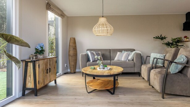 A spacious living room with a large window, a round coffee table, a sofa, and a cabinet.