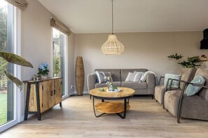 Un salon spacieux avec une grande fenêtre, une table basse ronde, un canapé et un meuble.