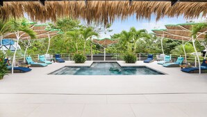 An outdoor swimming pool with lounge chairs and umbrellas, surrounded by greenery. - Family Villa w Resort-Style Pool - 5 Min to Beaches (Potrero)