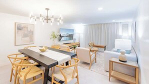 Una sala de estar moderna con comedor, televisor y sofá.