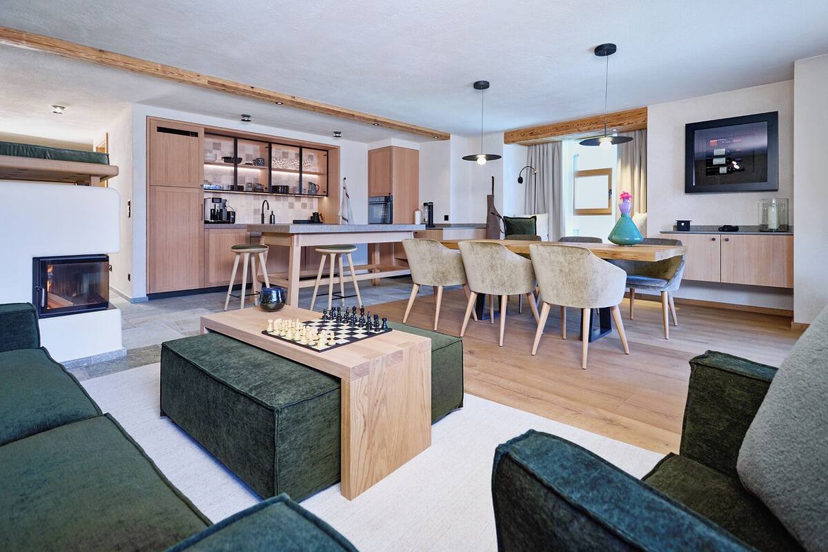 A modern living room with a chessboard, a fireplace, and a dining area with chairs and a table.