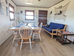 Un coin repas avec une table et des chaises en bois, un canapé et une petite table sur laquelle est posé un magazine.