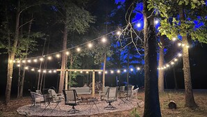 Ein möblierter Patio-Bereich im Freien mit Lichterketten und einer Holzpergola.