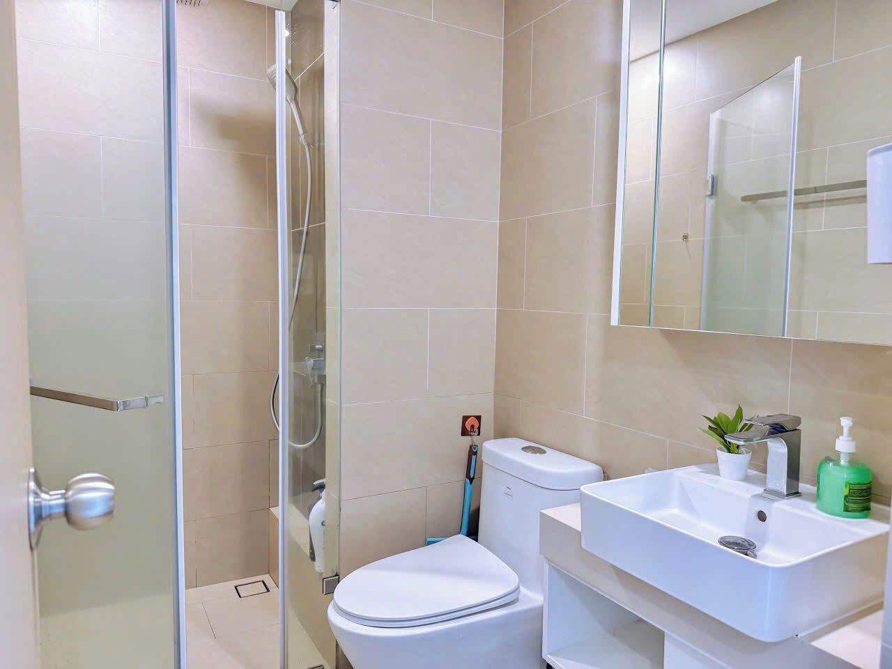 A bathroom with a glass shower enclosure, a white toilet, and a sink with a mirror above it.