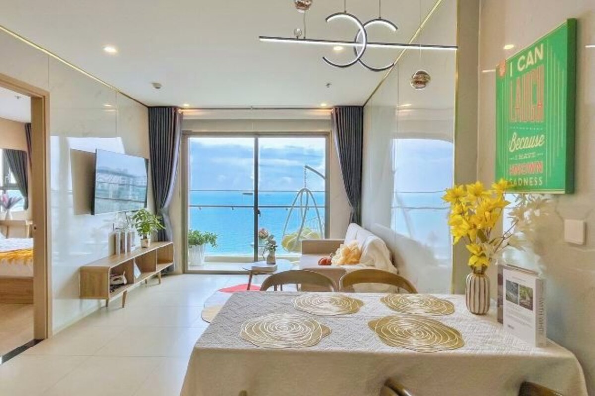 Een moderne hotelkamer met een groot raam, een zithoek met een tafel en uitzicht op zee.