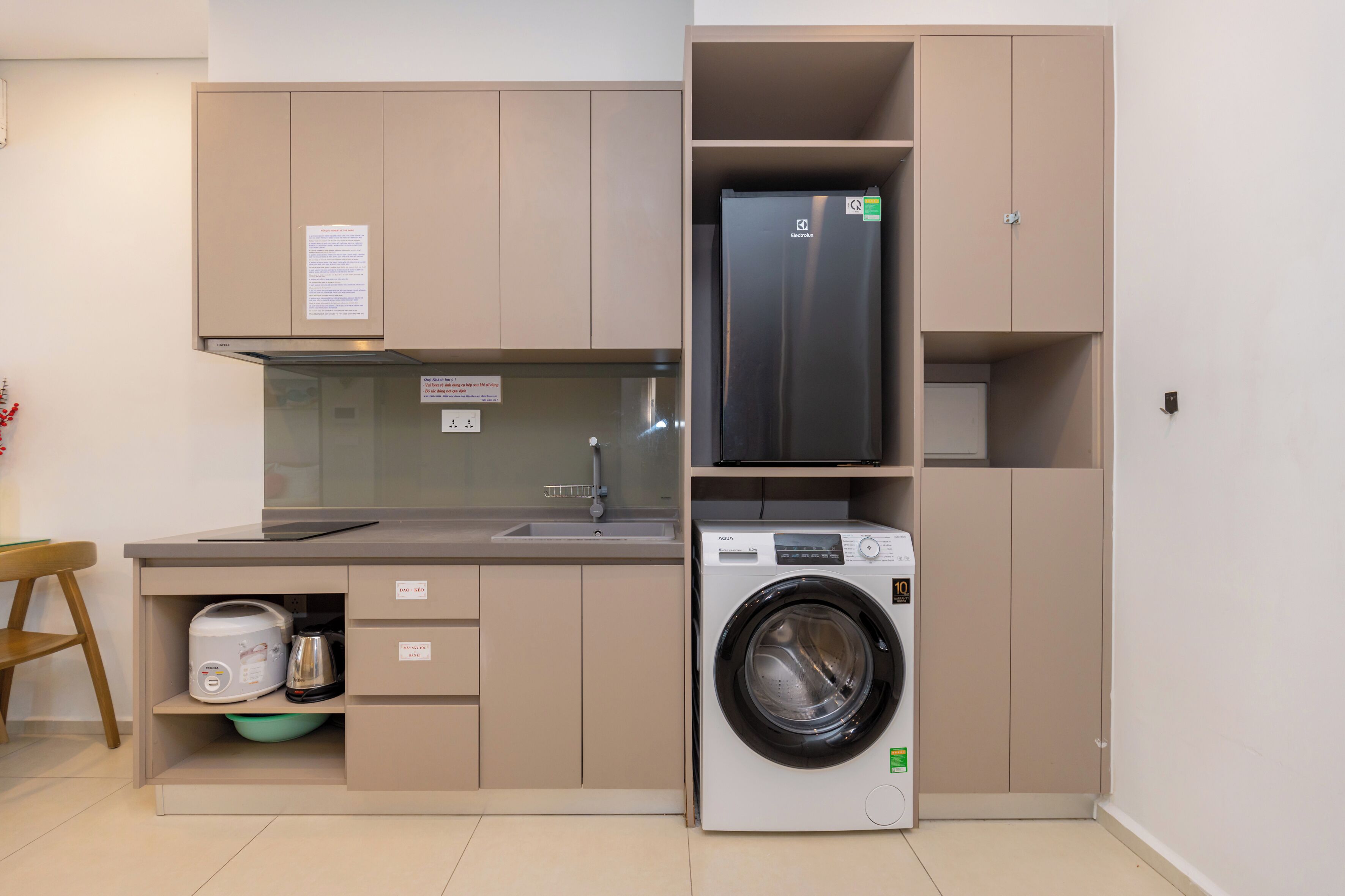 A compact kitchen with a built-in washing machine, a refrigerator, and a sink.