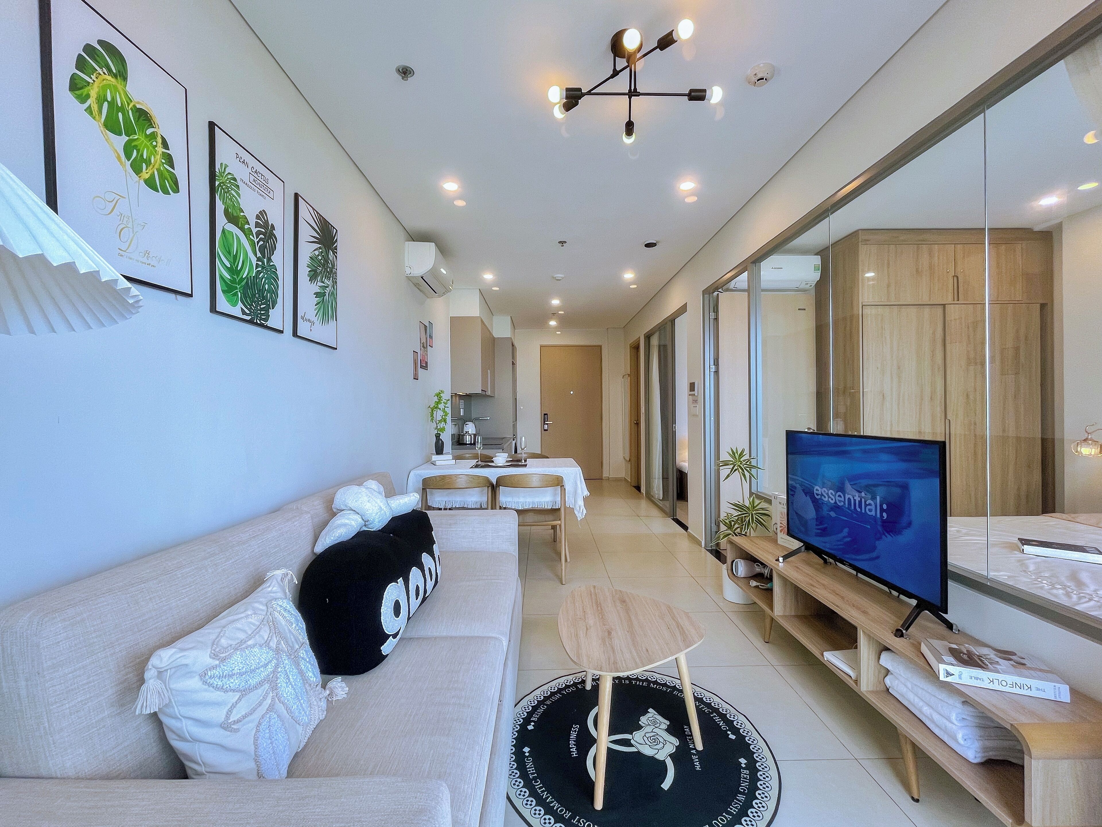A modern living room with a sofa, a coffee table, a TV, and a dining area with chairs and a table.
