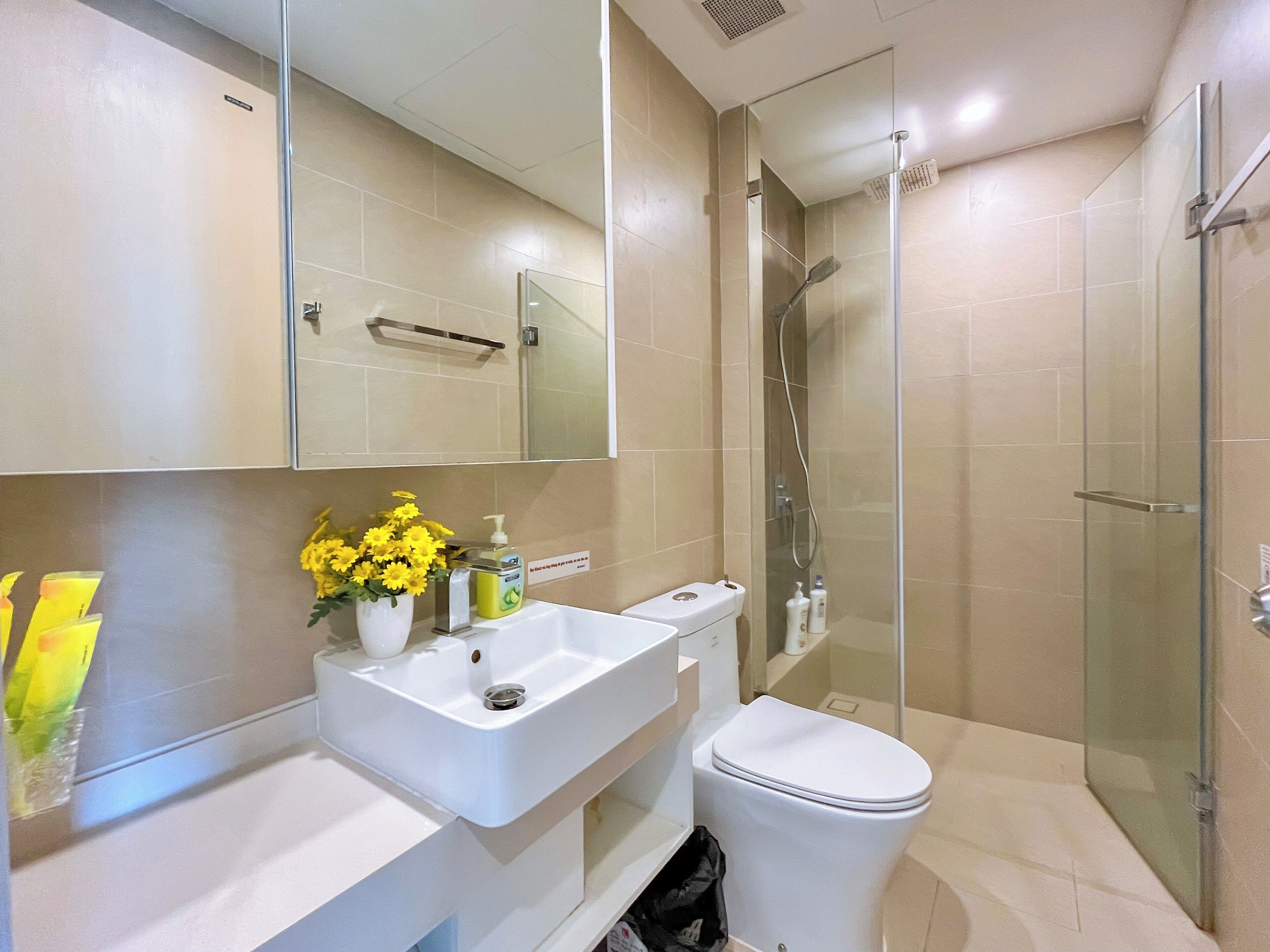A modern bathroom with a white sink, toilet, and glass-enclosed shower.