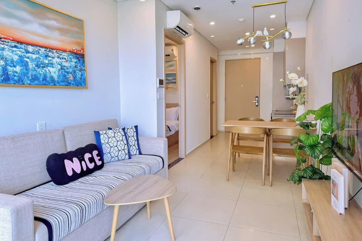 Un salon moderne avec un canapé, une petite table et un coin repas comprenant une table et des chaises en bois.