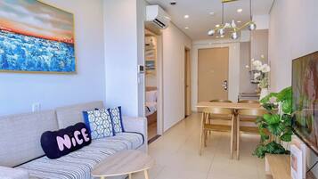 A modern living room with a sofa, a small table, and a dining area with a wooden table and chairs.