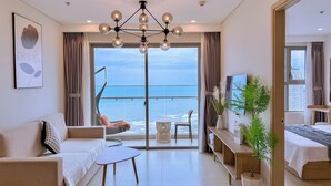 A modern living room with a balcony overlooking the sea, a hanging chair, a sofa, a small table, and a TV. - OLIU'S HOMESTAY - The Sóng Vũng Tàu (Ho Chi Minh City)