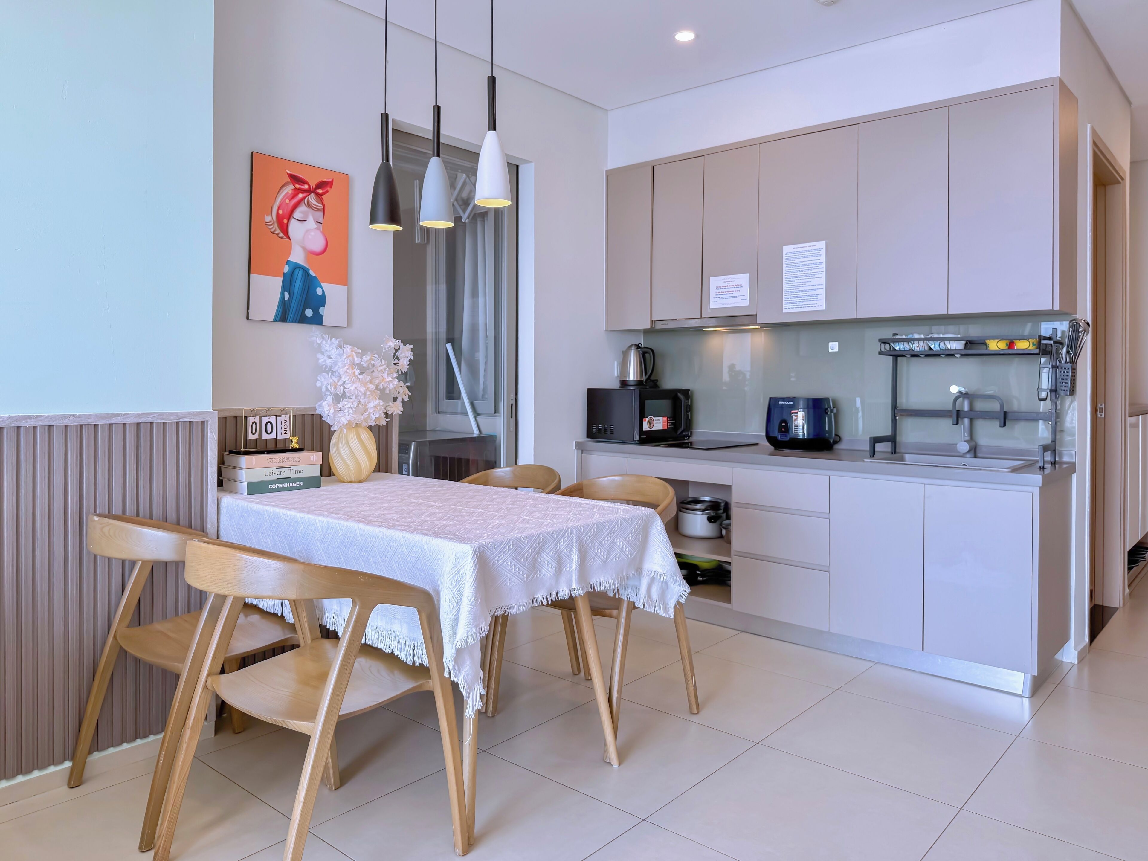 Une cuisine moderne avec un coin repas, comprenant une table avec des chaises, un four à micro-ondes, une machine à café et une bouilloire.