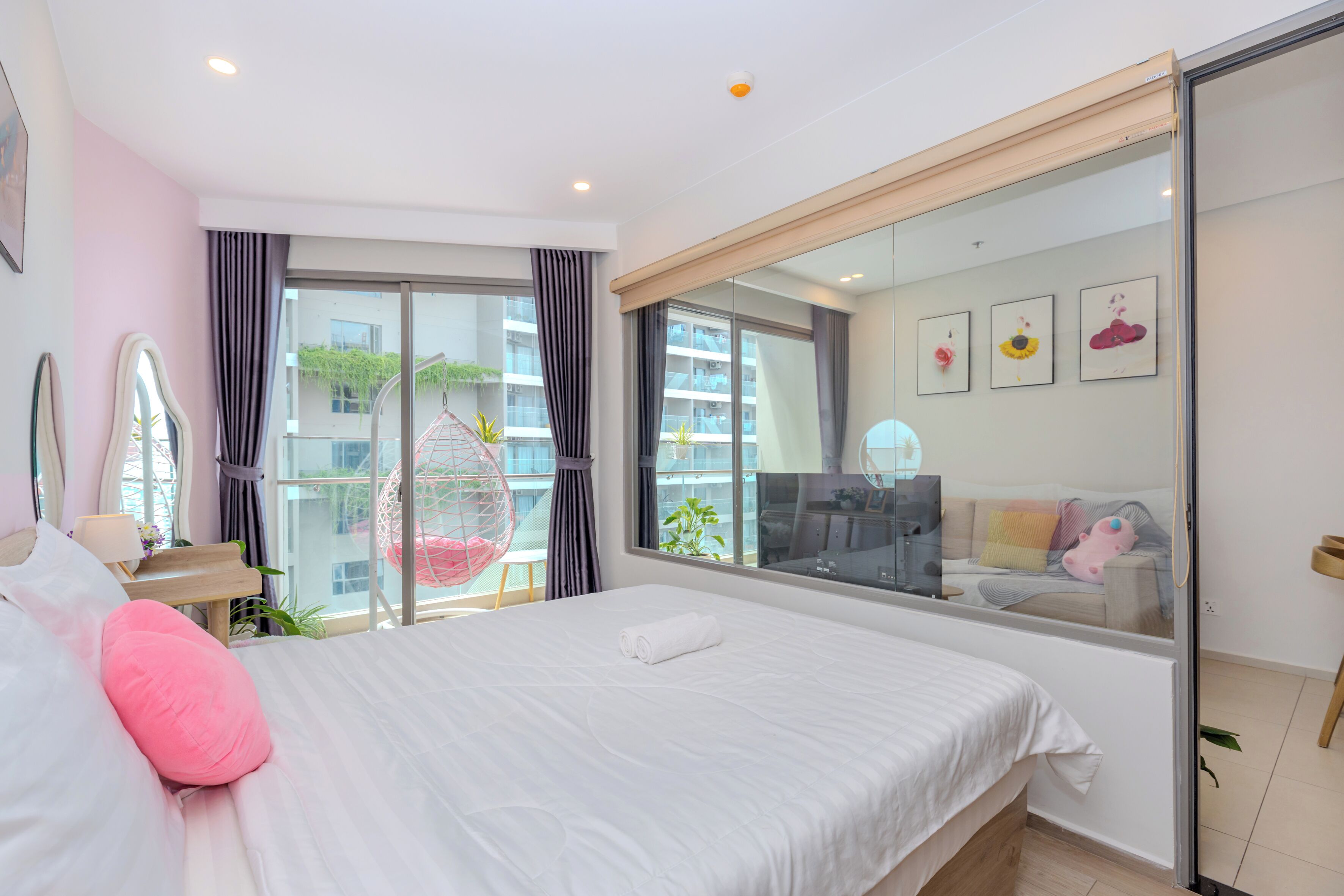 Una habitación de hotel moderna con una cama grande, un balcón con una silla colgante y vistas a la ciudad.