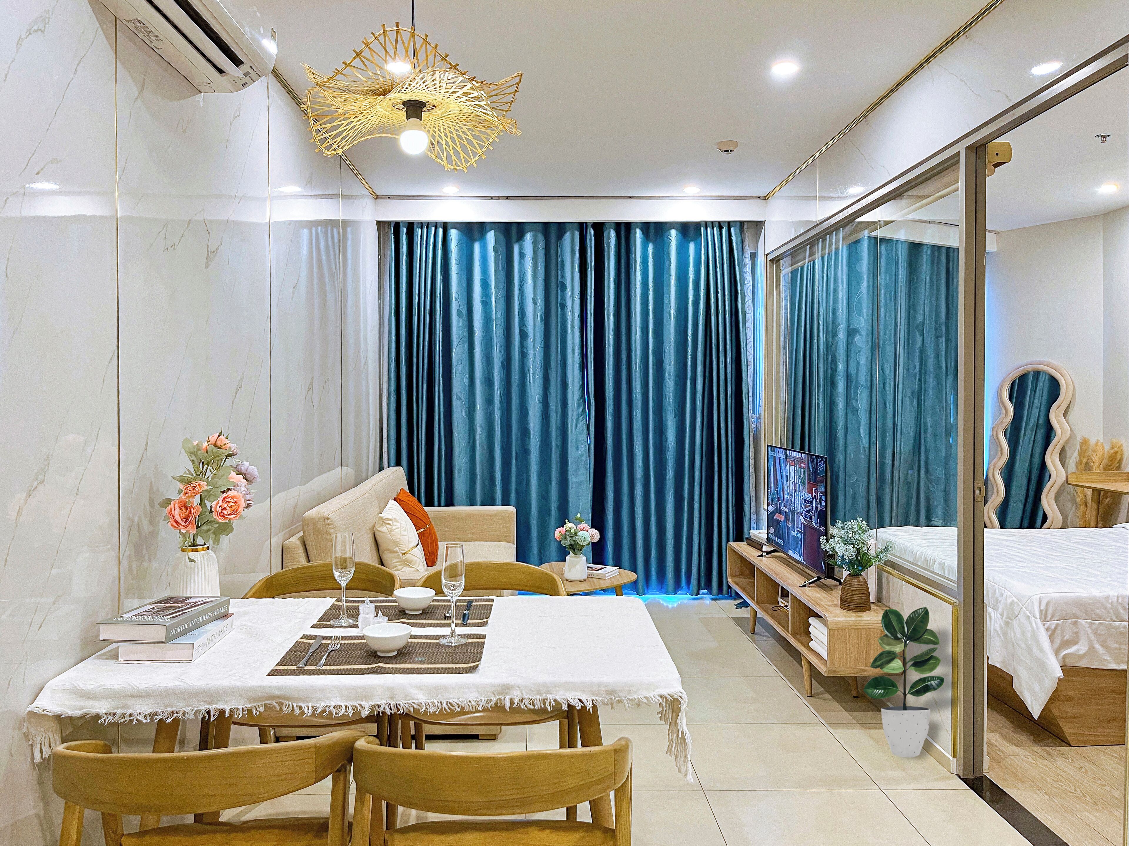 A hotel room with a dining area, a bed, a TV, and a large window with curtains.