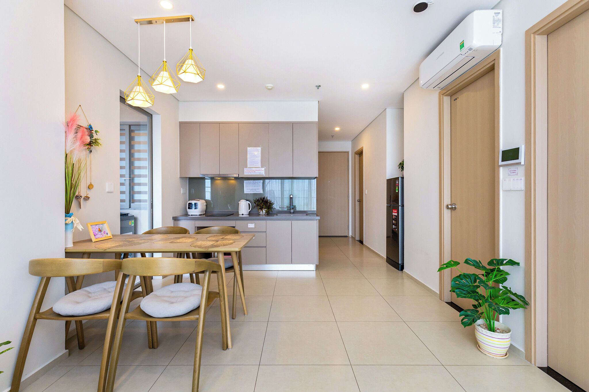 Una cocina moderna con comedor, que cuenta con una isla central, luces colgantes y una planta en maceta.