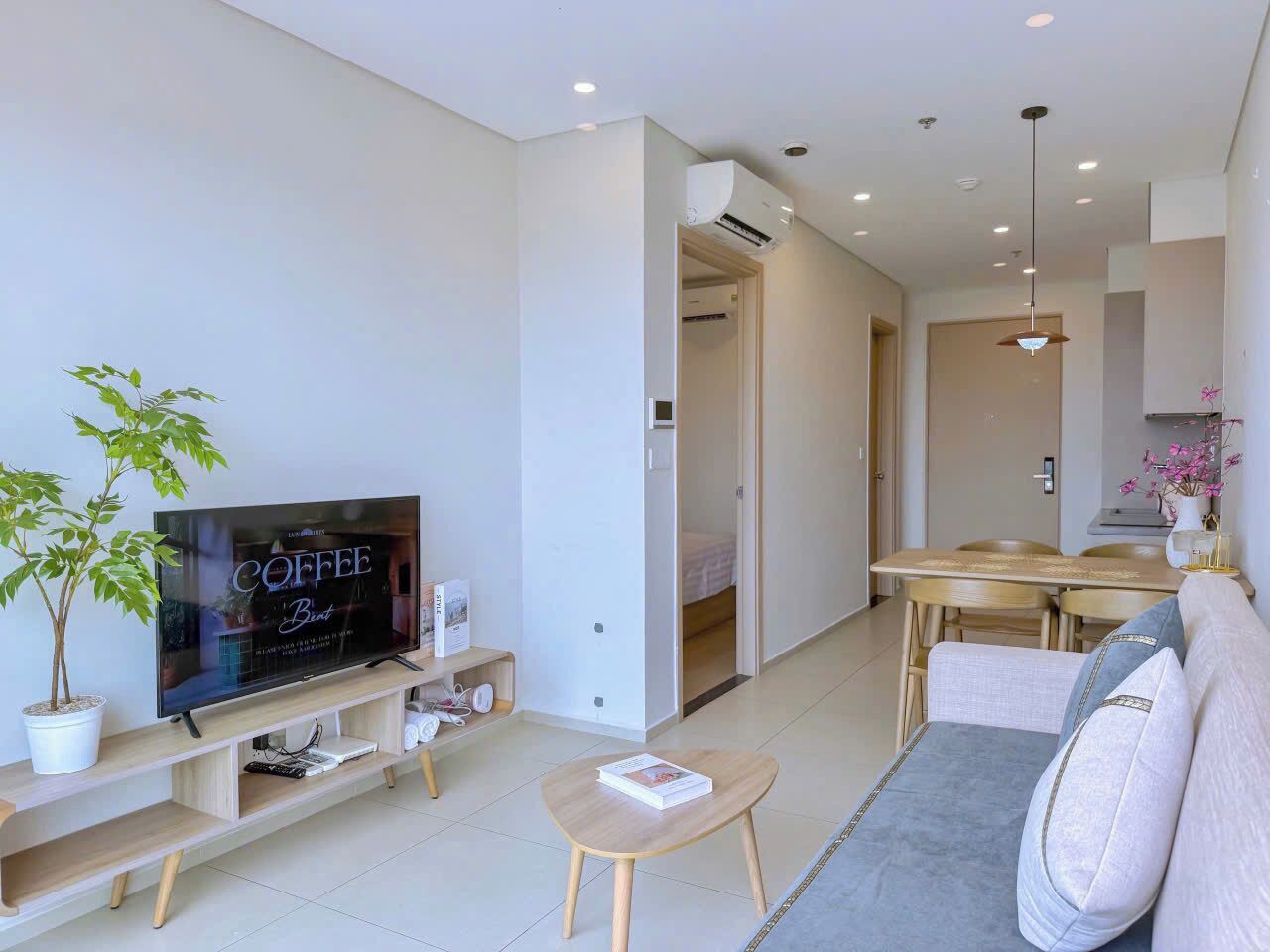 Una sala de estar moderna con un televisor de pantalla plana, un sofá, una mesa de centro y un comedor con una mesa y sillas.