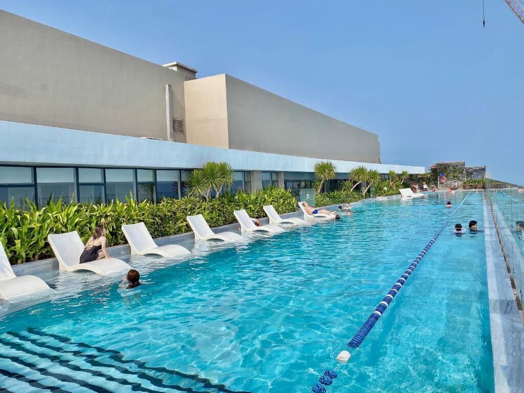 Una piscina con sillones de descanso y un edificio al fondo.