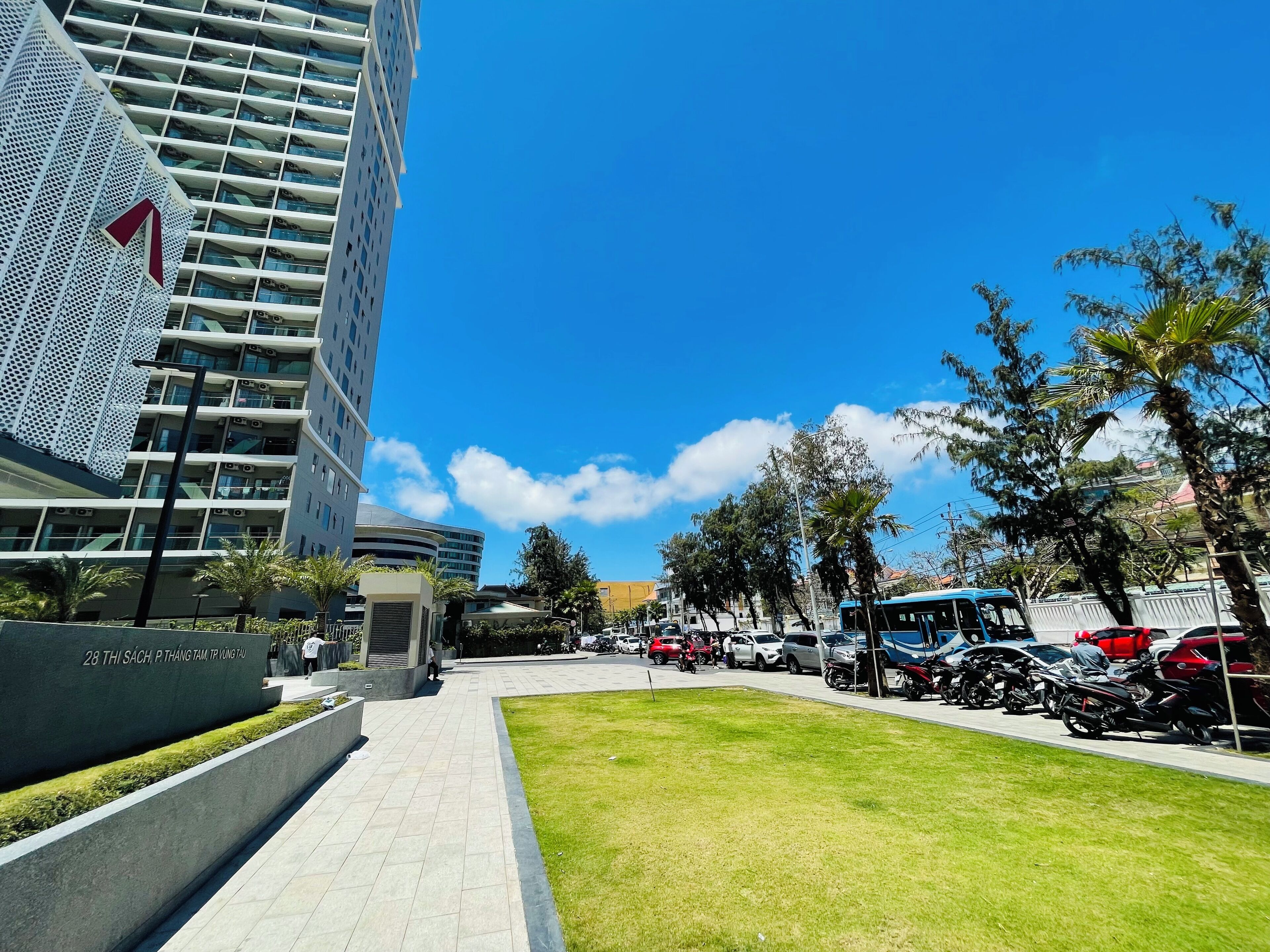 A modern building with a distinctive facade, a well-maintained grassy area, and parked vehicles.