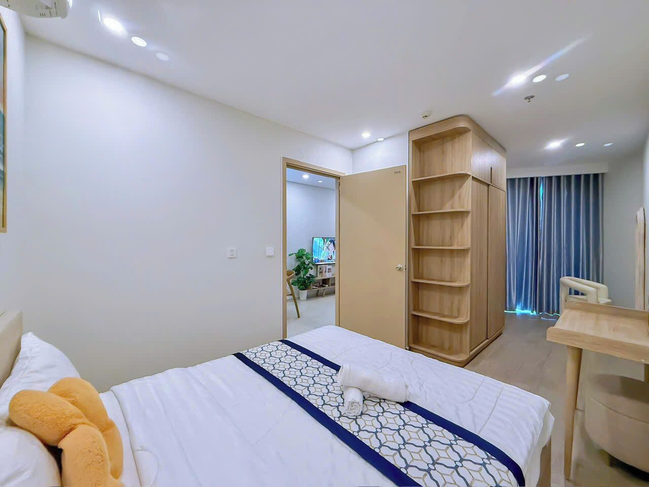 A hotel room with a bed, a wooden wardrobe, a desk, and a mirror.