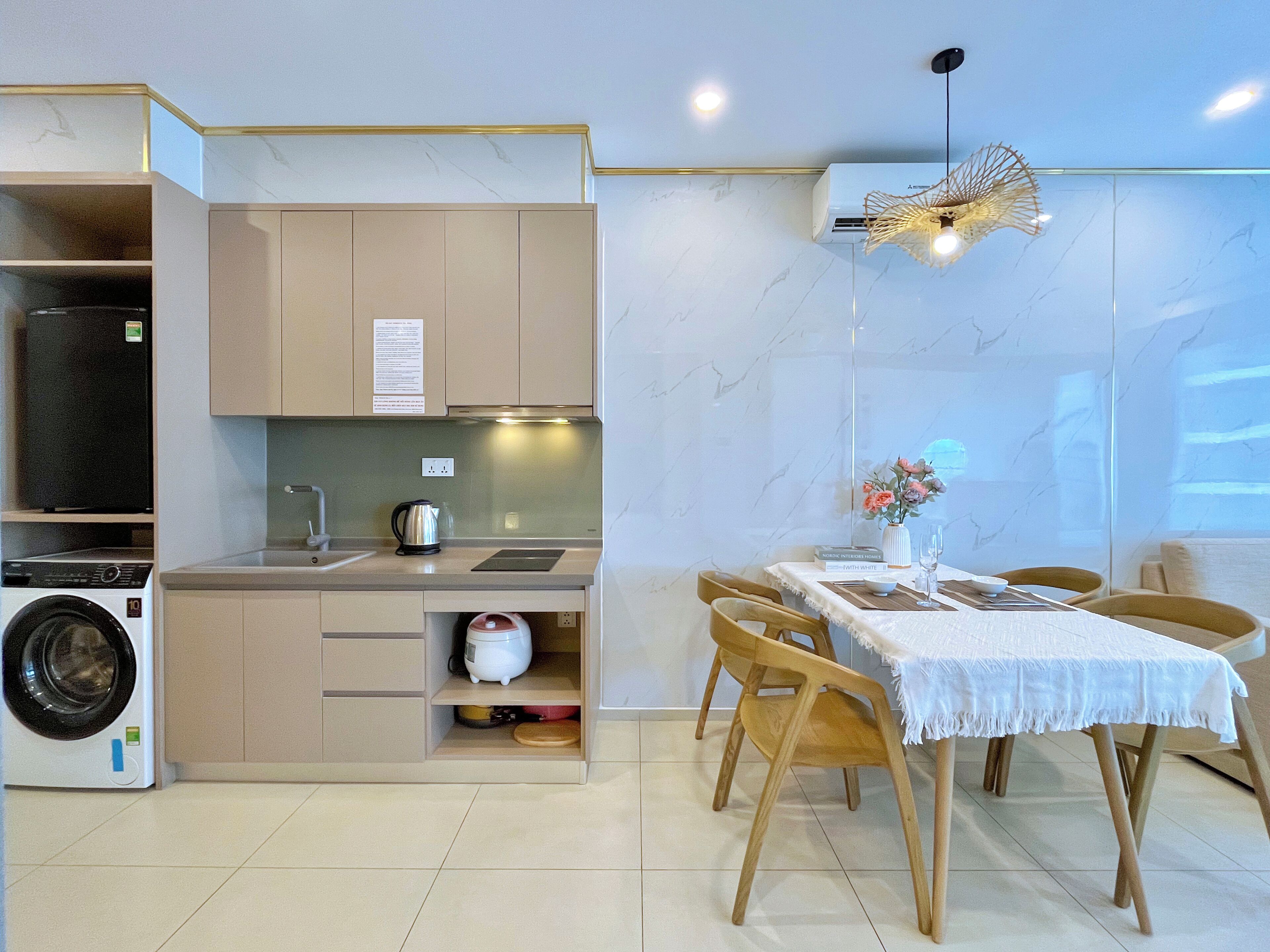 A compact kitchen with a washing machine, a coffee maker, and a dining area with a table and chairs.