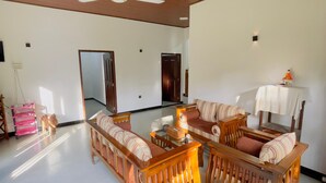 A spacious living room with a high ceiling, wooden furniture, and a ceiling fan. - Riverside Nature Haven Villa  (weligama)
