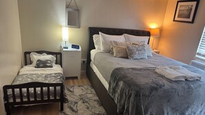 Une chambre à coucher comprenant un lit, une table de chevet, une petite table et un miroir fixé au mur.