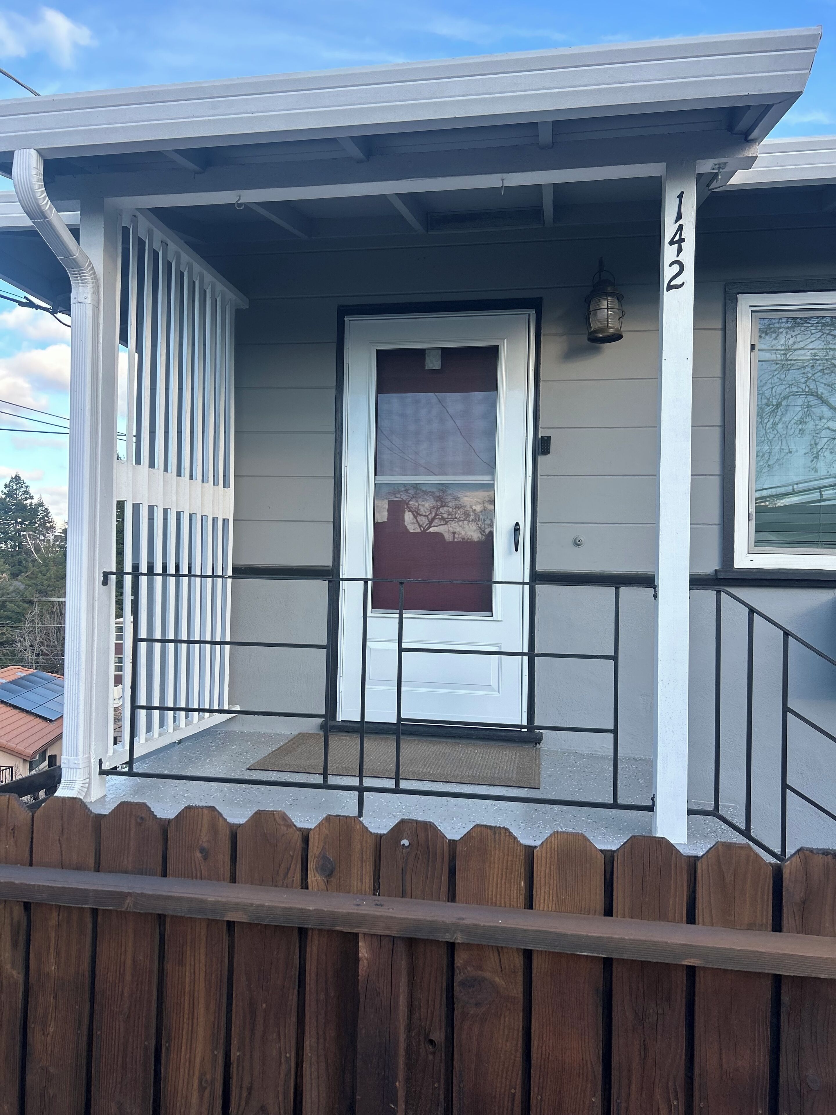 Une maison d’habitation avec un porche à l’avant, une porte blanche et une boîte aux lettres.