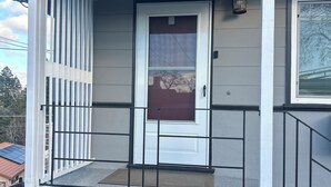 Une maison d’habitation avec un porche à l’avant, une porte blanche et une boîte aux lettres.