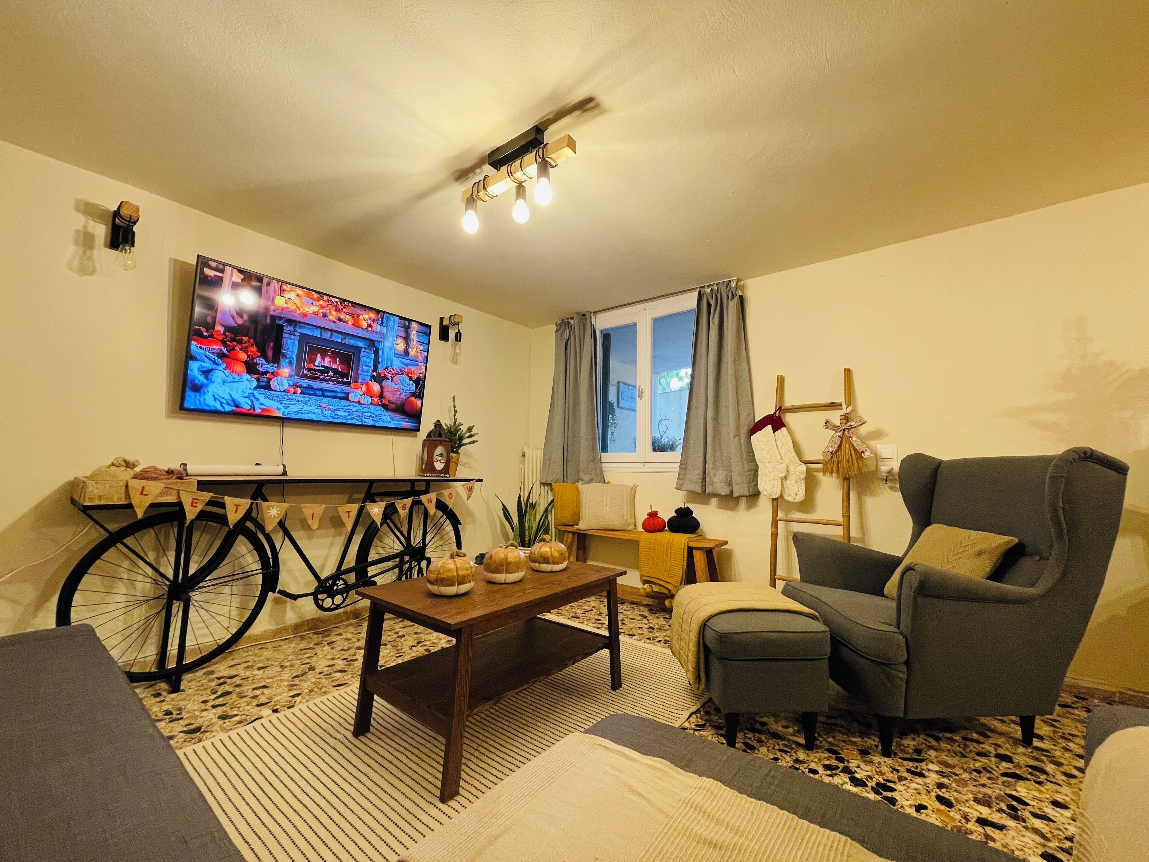 Una sala de estar acogedora con televisor, una bicicleta y un sillón.
