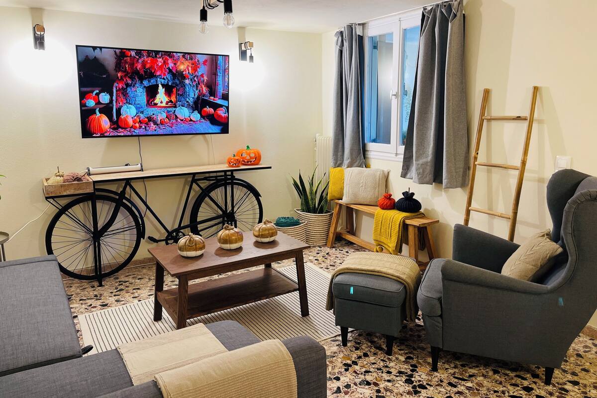 A living room with a television, a bicycle, a bench, and a chair.