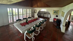 Un comedor con una mesa larga, sillas y una cocina al fondo.