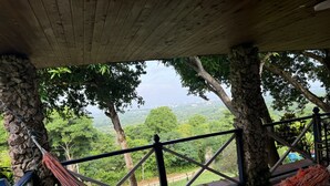 Una hamaca bajo una estructura de madera, con vista a un paisaje verde exuberante.