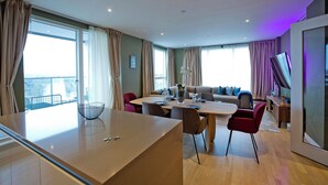 Moderni hotellihuone, jossa on ruokailutila, sohva ja televisio.